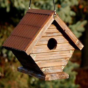 Rustic wooden wren house with corrugated metal roof hanging outdoors