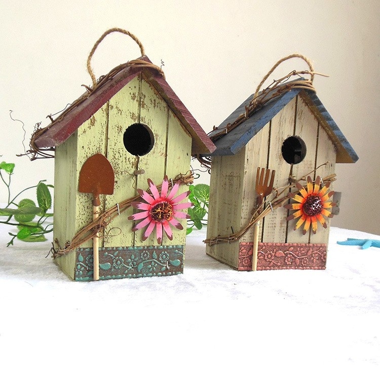 Rustic wooden hanging birdhouse painted green with blue roof, flower and garden tool accents - view 3