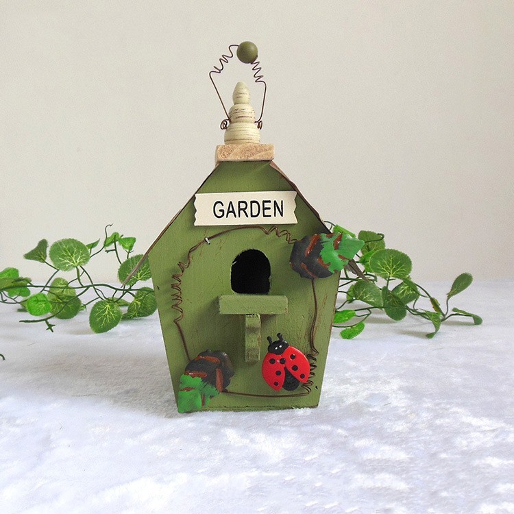 Rustic wooden hanging birdhouse painted green with blue roof, flower and garden tool accents - view 10