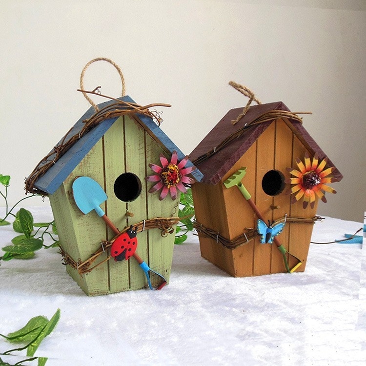 Rustic wooden hanging birdhouse painted green with blue roof, flower and garden tool accents - view 5