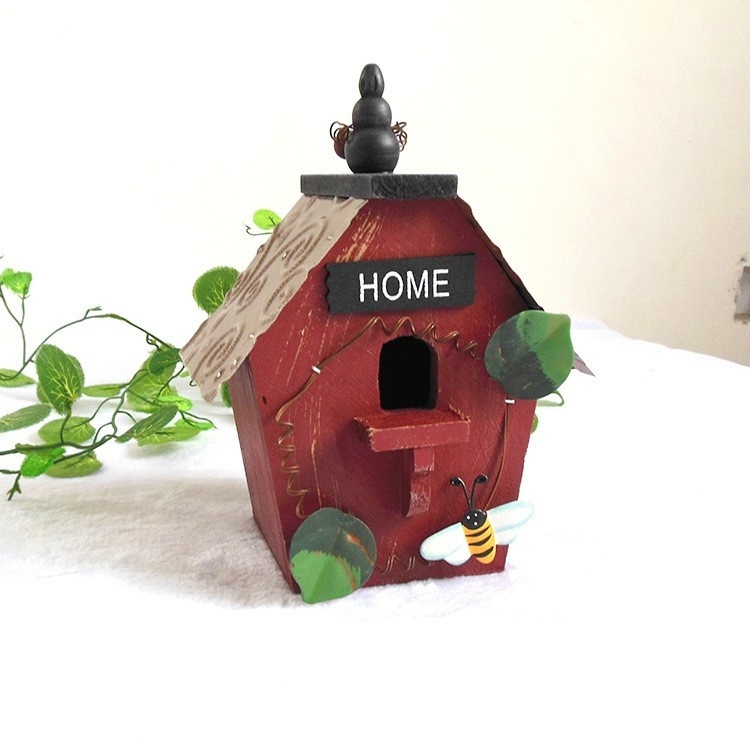 Rustic wooden hanging birdhouse painted green with blue roof, flower and garden tool accents - view 2