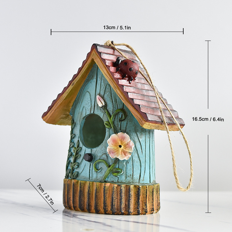 Rustic resin hanging birdhouse in turquoise with orange roof and leaf details hanging in a fig tree - view 9