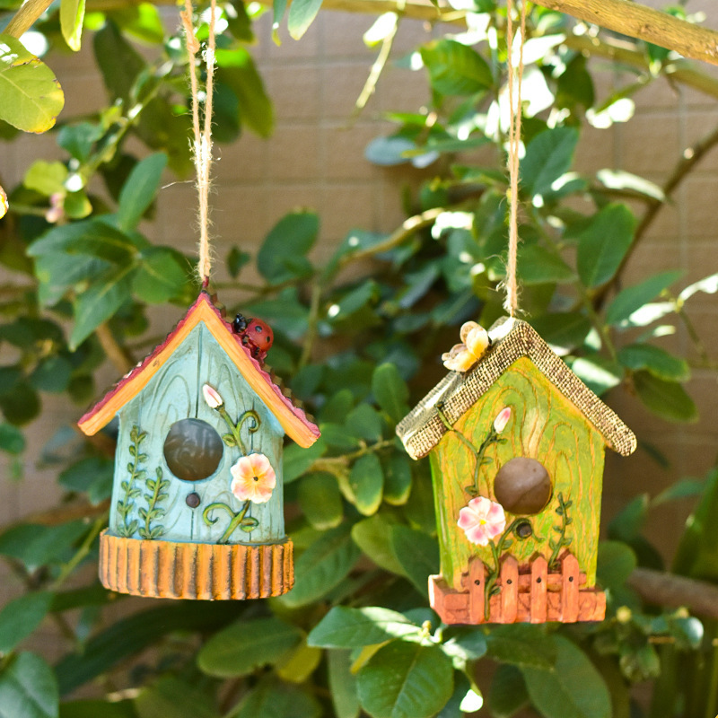 Rustic resin hanging birdhouse in turquoise with orange roof and leaf details hanging in a fig tree - view 7