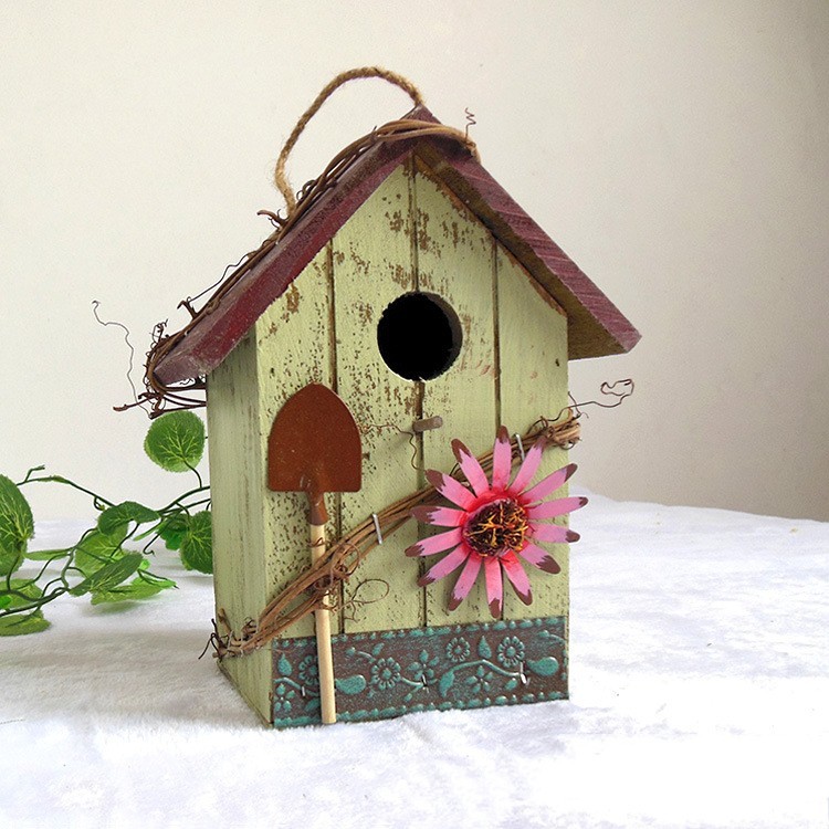 Rustic wooden hanging birdhouse painted green with blue roof, flower and garden tool accents - view 7