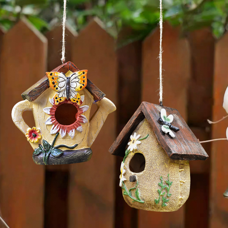 Rustic resin hanging birdhouse in turquoise with orange roof and leaf details hanging in a fig tree - view 2